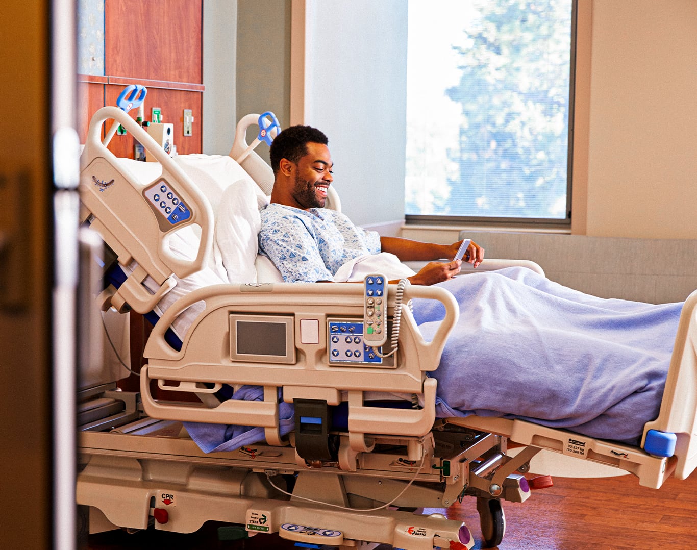 A patient smiling at a phone in a hospital room