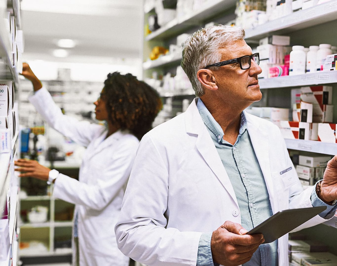 Two clinicians looking for medication in a pharmacy